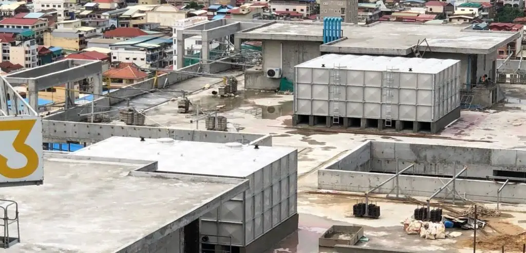 FRP sectional water tank installation at Olympia City, Cambodia – elevated view of two completed tanks on the building rooftop