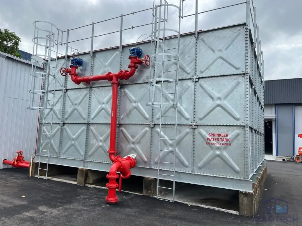 HDG pressed steel water tank installation at 18 Pandan Road, Singapore – completed sprinkler water tank with red fire protection pipework, access ladders and safety guardrails.
