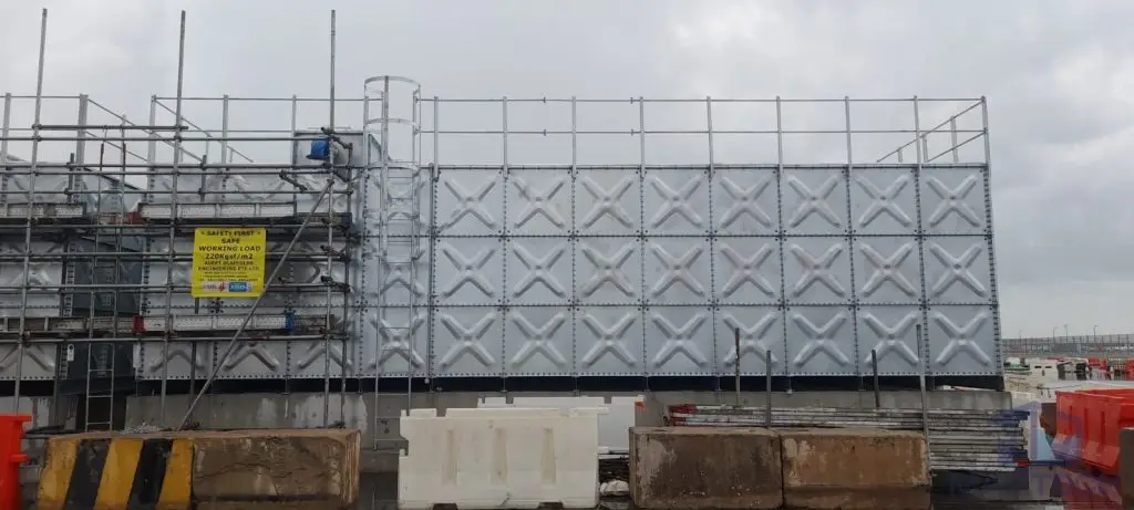 Hot-dipped galvanized pressed steel water tanks at ARC Changi T5, Singapore – HDG tank installation with scaffolding and roof access ladder