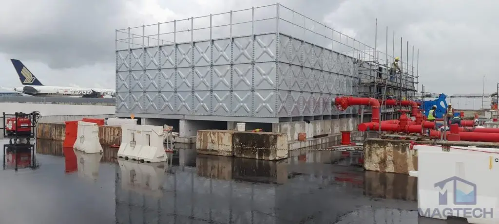Hot-dipped galvanized pressed steel water tanks at ARC Changi T5, Singapore – completed installation beside fire protection pipes at the airport site