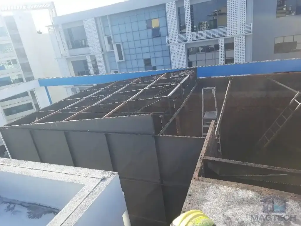 Water tank cover replacement and structural roof support renewal at AMA Building, Singapore – exposed tank roof support framework during replacement
