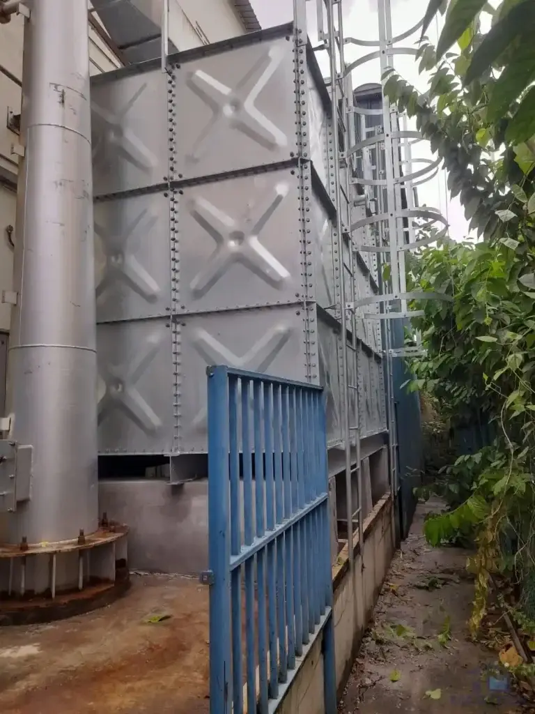 HDG pressed steel water tank installation at 71 Tuas View Loop, Singapore – completed sectional tank beside industrial pipework and access gate