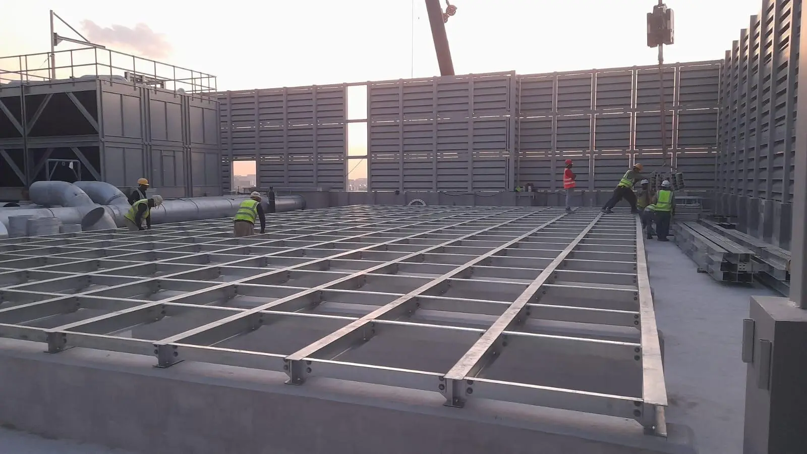 A group of workers installing a commercial water tank within a steel frame structure of a new building-water tank replacement cost Singapore