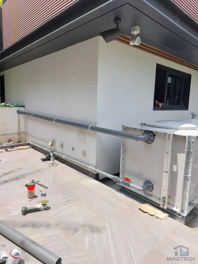 FRP rainwater tank installation at 36 Fifth Avenue, Singapore - completed tank installed along the house with connected pipework